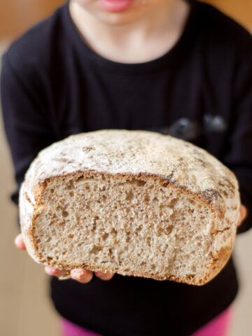 chleb trzymany w dłoniach przez dziewczynkę