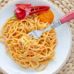 Spaghetti z paprykowym pesto na białym talerzu