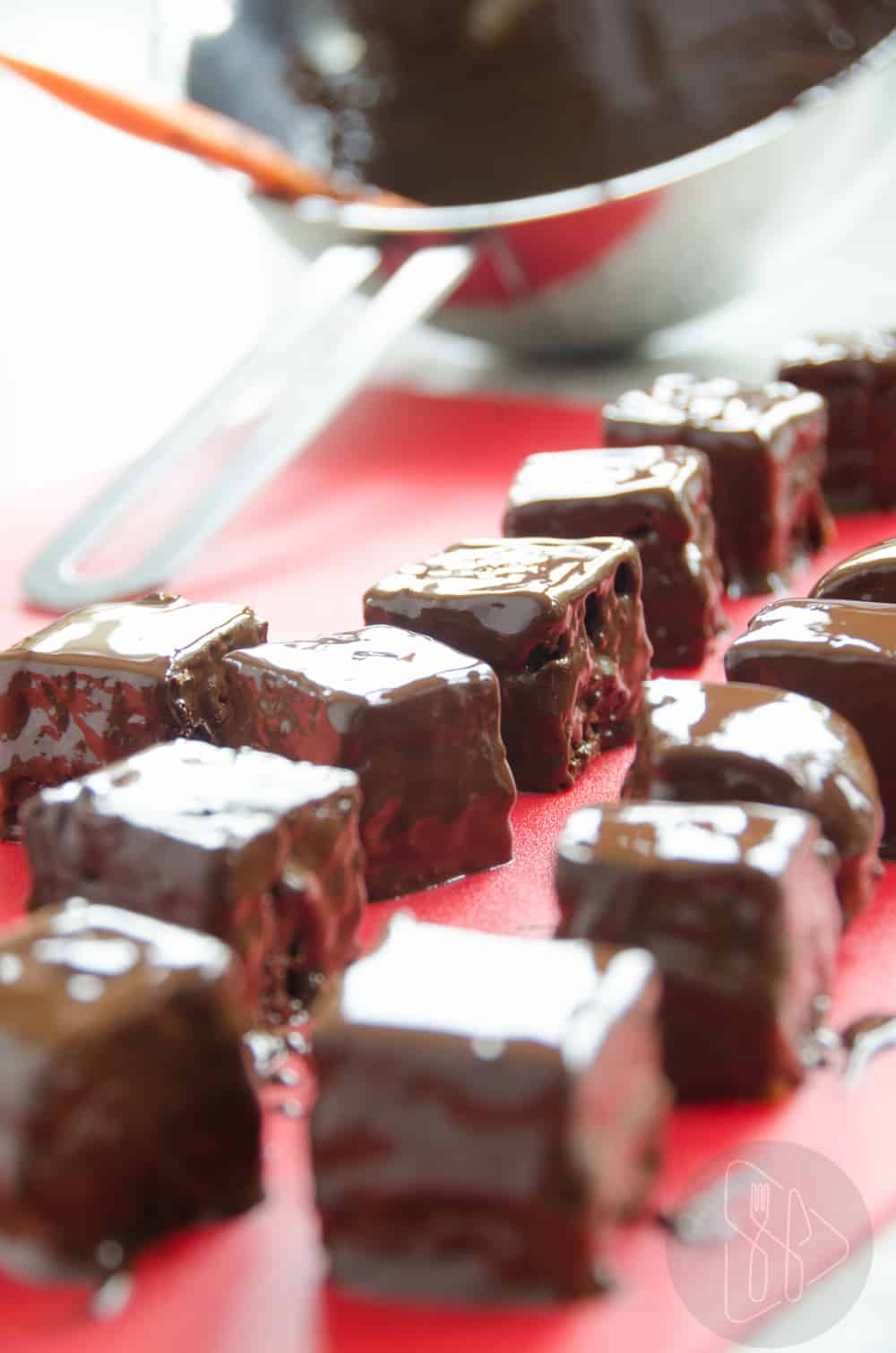 Pierniczki domino polane czekoladą w  tle miska z czekoladą.
