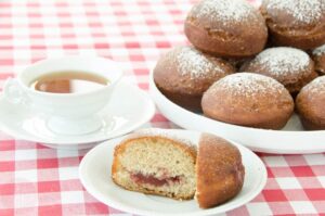pączki orkiszowe ułożone na talerzu, na pierwszym planie przeekrojony pączek z nadzieniem