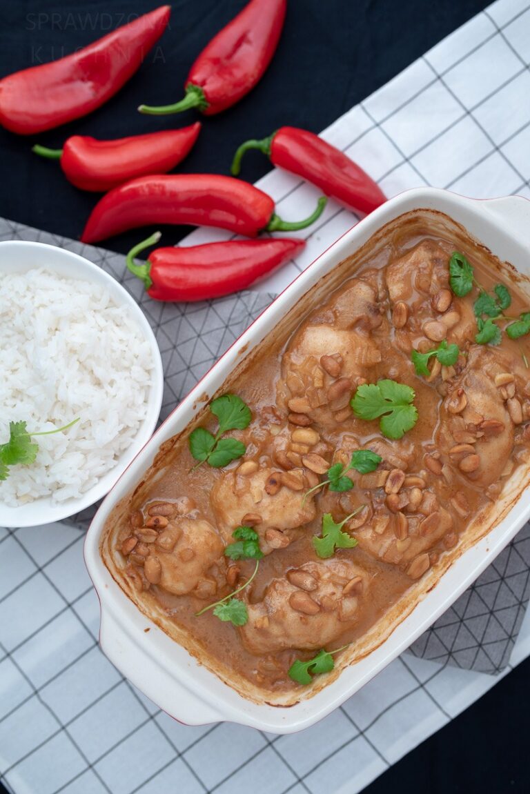 kurczak w sosie orzechowym w naczyniu ceramicznym na stole, obok ryż i papryczki chilli