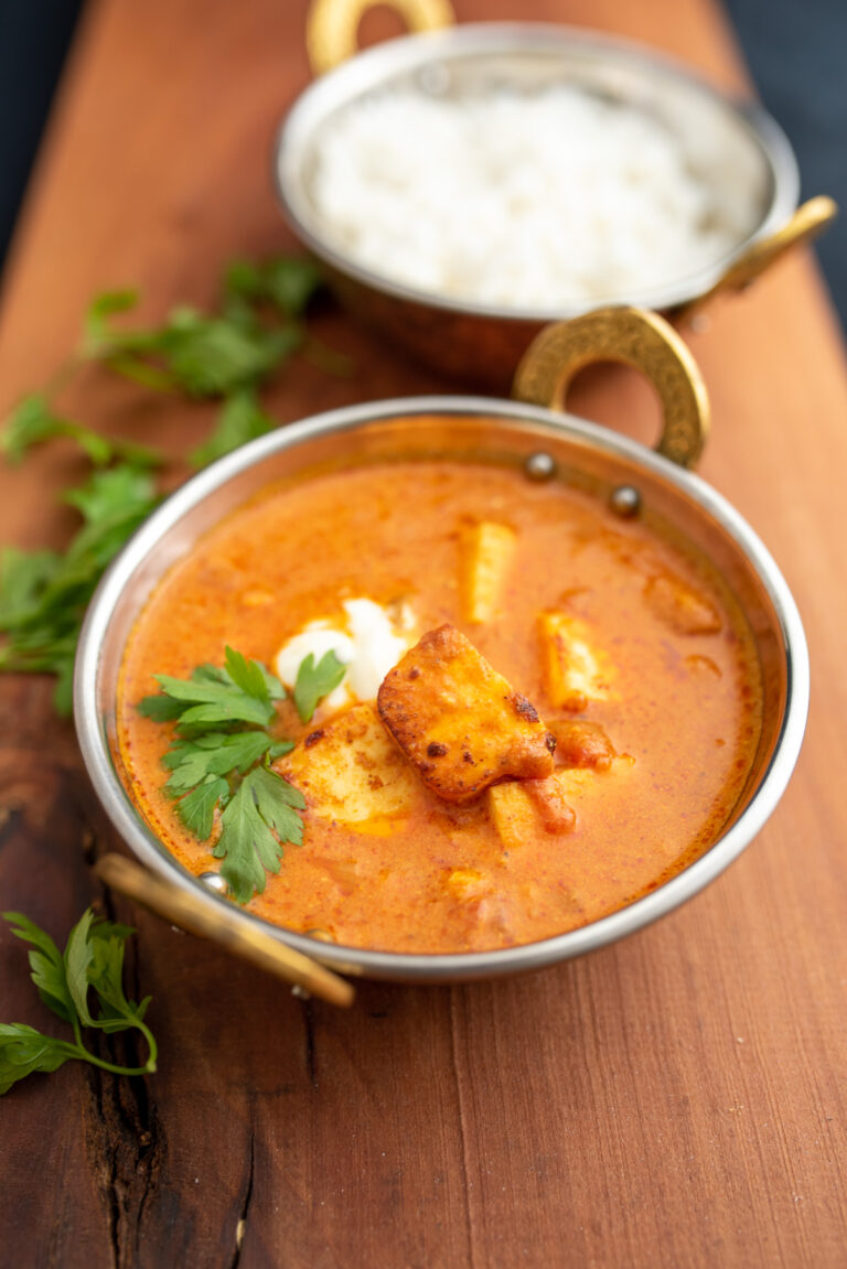 Ser paneer w sosie w miedzianych miseczkach w tle miseczka z ryżem