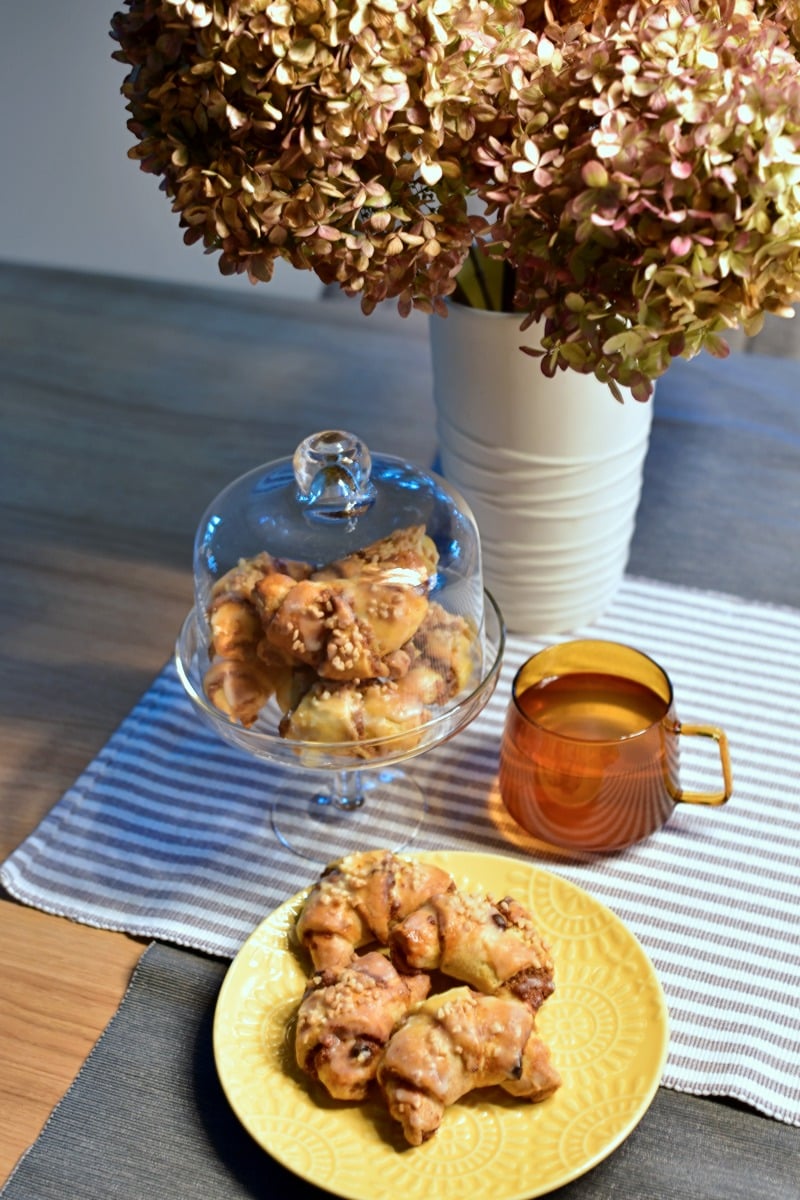 mini rogaliki św. Marcina podane na talerzyku w tle kwiaty i patera z rogalikami w szklance herbata