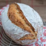 domowy chleb pszenny x rumianą skórka, ułożony na podstawce, pod podstawka ściereczka z pomarańczpwe kurki