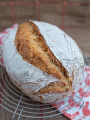 domowy chleb pszenny x rumianą skórka, ułożony na podstawce, pod podstawka ściereczka z pomarańczpwe kurki