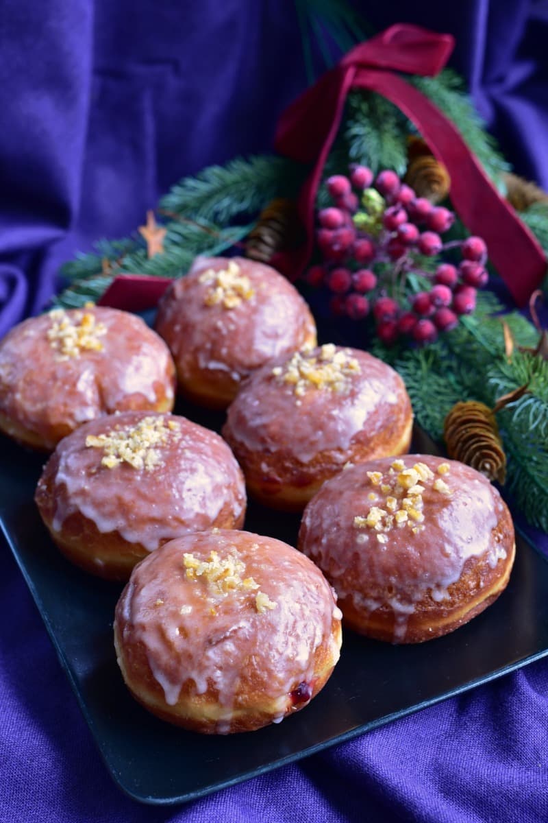 lukrowane pączki na czarnym talerzu w tle gałązka świerkowa z ozdobami