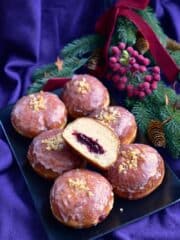 pączki lukrowane na talerzu jeden z nich przekrojony ukazujący nadzienie