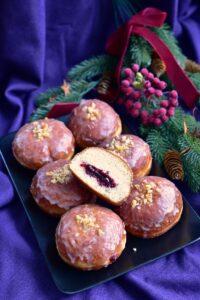 pączki lukrowane na talerzu jeden z nich przekrojony ukazujący nadzienie